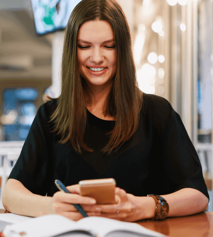 Um homem sorridente falando ao celular e usando o computador