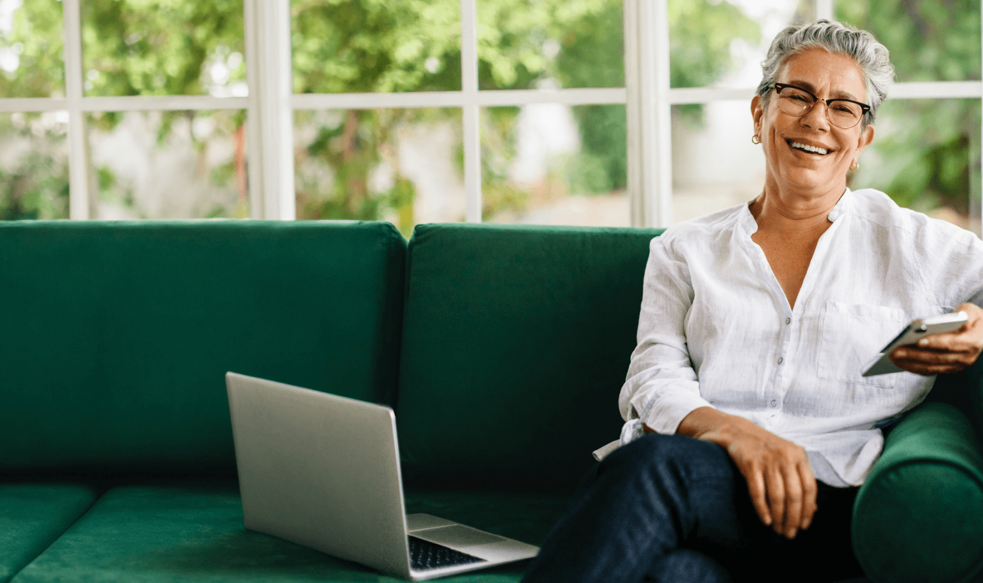 Uma mulher sorridente segurando uma xícara e mexendo no computador