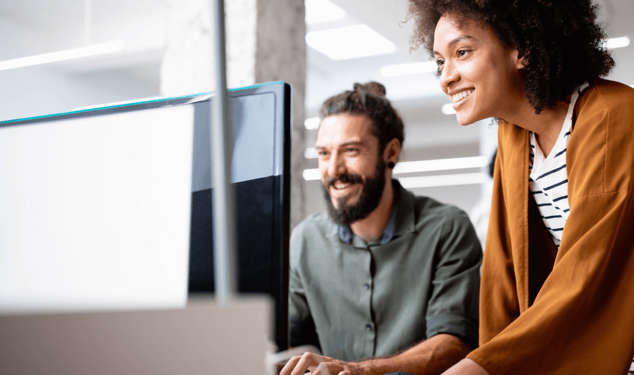 Uma mulher sorridente segurando uma xícara e mexendo no computador