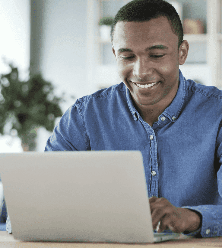 Um homem sorridente falando ao celular e usando o computador