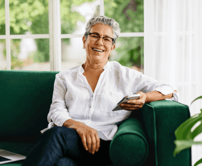 Uma mulher sorridente segurando uma xícara e mexendo no computador